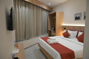 a hotel room with a bed and a flat screen tv at The Bhavani Hotel in Dāhod +45 photos