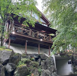a building with a garage in front of some rocks at Lodge Kurokawa 2 Forest in Minamioguni