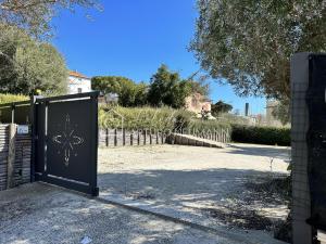 a black gate with a sign on it in a driveway at 207 - VILLA FERNANDA - Bilocale di charme al piano terra immerso nel verde, in centro e a pochi passi dal mare SPIAGGIA AL WHITE BEACH CLUB IN OMAGGIO dal lun al ven dal 24-08 in Sirolo