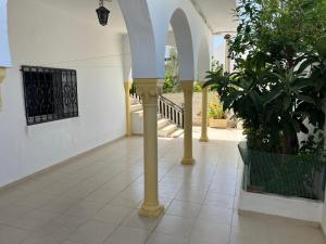 a hallway with columns and plants in a building at Charmante maison à Hammamet, proche plage et commodités in Hammamet