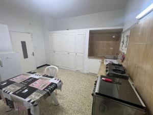 a kitchen with a stove and a table in it at Charmante maison à Hammamet, proche plage et commodités in Hammamet