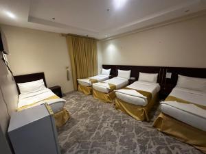 a row of four beds in a room at غرف تاج الذهبية الملاوي in Mecca