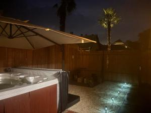 a hot tub with an umbrella on a patio at night at Góré Vendégház in Abony