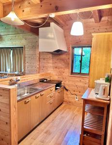 a kitchen with wooden walls and wooden floors at Lodge Kurokawa 2 Forest in Minamioguni
