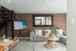 a living room with a couch and a brick wall at Lovemore Retreat in Gqeberha