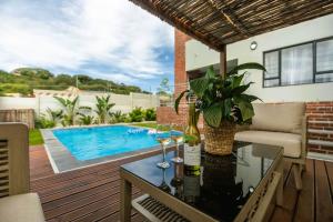 a patio with a table with wine glasses and a swimming pool at Lovemore Retreat in Gqeberha