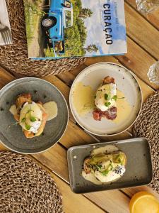 two plates of food on a table with a book at Yucca mini boutique hotel - Adults only in Jan Thiel