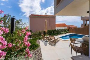 a backyard with a swimming pool and pink flowers at Villa Cvita east in Primošten