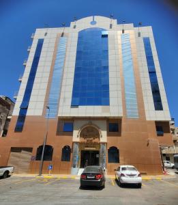 two cars parked in a parking lot in front of a building at غرف تاج الذهبية الملاوي in Mecca