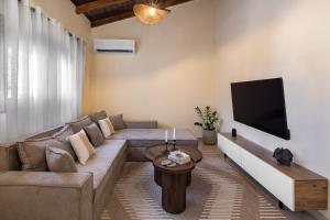 a living room with a couch and a flat screen tv at TheraLiving - Boutique Apartment with Balcony in Afantou
