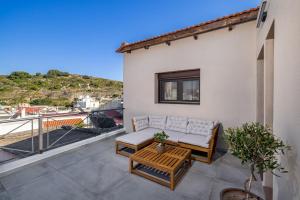 a patio with a couch and a table on a balcony at TheraLiving - Boutique Apartment with Balcony in Afantou
