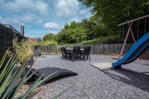 a patio with a table and chairs and a slide at Les Gîtes de Sprimont - Le Cottage in Sprimont