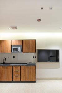 a kitchen with wooden cabinets and a microwave and a tv at هوليدي الخليج الفندقية Holiday Alkhaleej in Riyadh