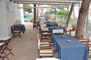 a row of tables and chairs with blue table cloths at Hotel Garden in Lignano Sabbiadoro