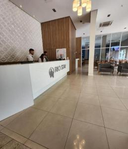 a lobby of a restaurant with two people sitting at a counter at Flat & Suite Premium - Rio Centro - Barra - Farmasi Arena in Rio de Janeiro +41 photos