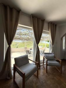 a living room with two chairs and a large window at Holiday house Bore in Babino Polje +18 photos