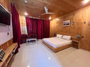 a bedroom with a bed and a tv in it at Relax Cottages & Resort Kalam in Kalām