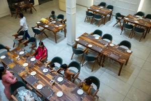 a group of people sitting at tables in a restaurant at Aayovea Resort Ayodhya Near Ram Mandir & Saryu River in Ayodhya