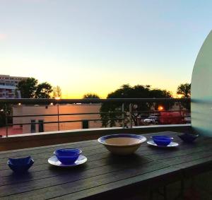 a wooden table with bowls and plates on a balcony at VistaMare Bluemar - Garden & Sea in Cattolica