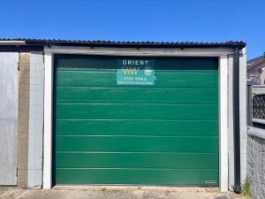 a green garage door with a sign on it at Orient Short Stay in Holyhead