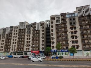 a large apartment building with cars parked in a parking lot at Margalla Hills View Apartment Islamabad in Islamabad