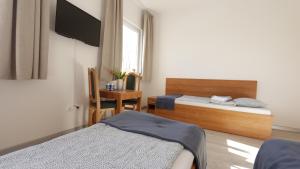 a bedroom with two beds and a desk and a television at Baltic Resort - Korsarz in Darłowo