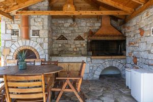an outdoor kitchen with a table and a stone fireplace at Archontiko Koufantonis in Kotronas