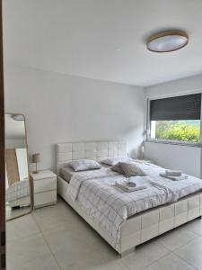 a white bedroom with a large bed and a window at Hiša Naj in Koper