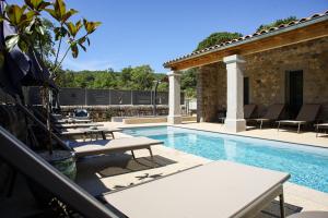 a swimming pool with lounge chairs and a house at Hôtel La Garenne in Labeaume