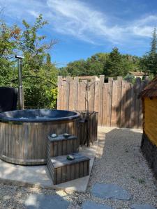 a hot tub in a backyard with a wooden fence at La cabane escagassée in Grambois +2 photos