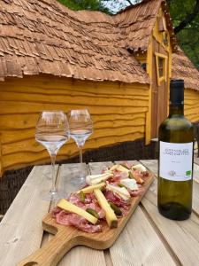 a table with two wine glasses and a plate of meat and cheese at La cabane escagassée in Grambois