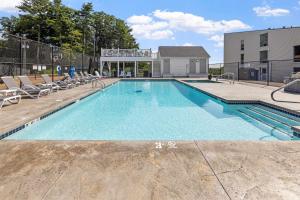 a swimming pool with chairs and a building at Cedar Lodge Condo with Private Balcony & Full Kitchen in Laconia