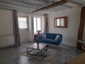 a living room with a blue couch and a table at Le lit de la SEINE in Saint-Seine-lʼAbbaye