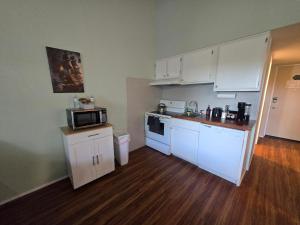 a small kitchen with white cabinets and a microwave at Cedar Lodge Condo with Private Balcony & Full Kitchen in Laconia