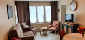 a living room with a couch and chairs and a tv at Chemin vert in Bayeux