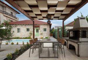 a patio with a table and chairs and a grill at Pnoe Luxury Villa - Private Pool Retreat & BBQ in Ierissos