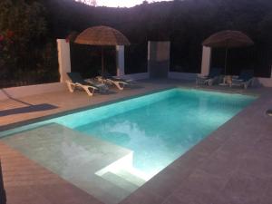 a swimming pool with chairs and umbrellas on a patio at Stunning views, 3 bed, private pool, olive grove in Iznájar