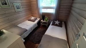 two beds in a room with wooden walls at Genuine Beach House and Sauna in Pello
