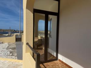 a balcony with glass doors with a view of the ocean at Peniche Surf & Sunset House in Peniche