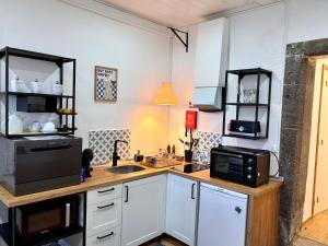 a kitchen with a counter with a microwave and a sink at Casinha do Solar in Angra do Heroísmo