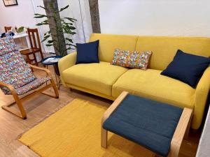 a living room with a yellow couch and chairs at Casinha do Solar in Angra do Heroísmo