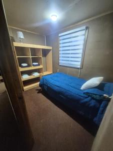 a bedroom with a blue bed and a window at Cabaña Gazul in Porvenir