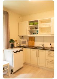 a kitchen with white cabinets and a sink and a microwave at Rekkehus Tyssedal Trolltunga in Tveit