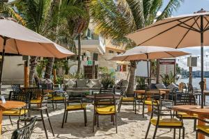 an outdoor patio with tables and chairs and umbrellas at The Carmen Hotel - Ocean Front in Playa del Carmen +68 photos