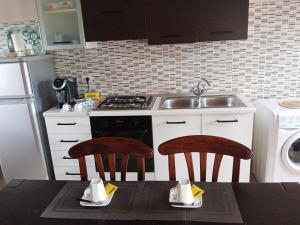 a kitchen with a stove and a sink and two chairs at Le vigne in Asti