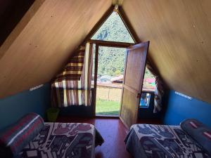 a attic room with two beds and a large window at Salkantay Lodge Collpapampa in Colcapampa
