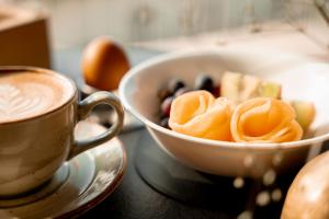 Eine Schale mit Obst und eine Tasse Kaffee auf einem Tisch in der Unterkunft Panoramahotel Watles in Mals im Vinschgau