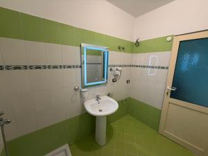 a green and white bathroom with a sink and a mirror at Rei Apartments in Sarandë +30 photos