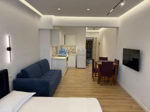 a living room with a blue couch and a kitchen at Rei Apartments in Sarandë