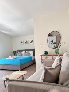 a bedroom with a bed and a couch and a mirror at green & blue villa in Glykadi